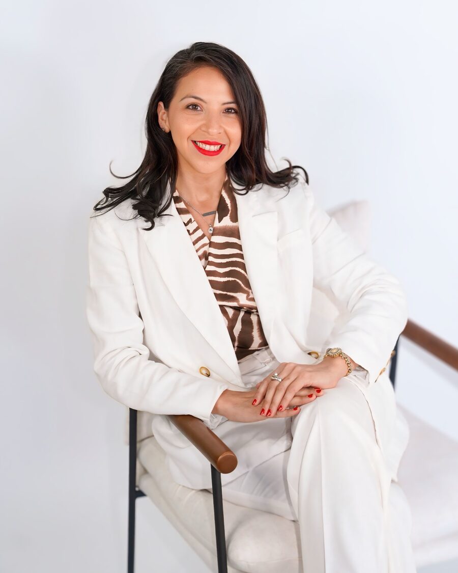Mayra Cordero, licensed Central Florida REALTOR, seated and smiling in a white suit